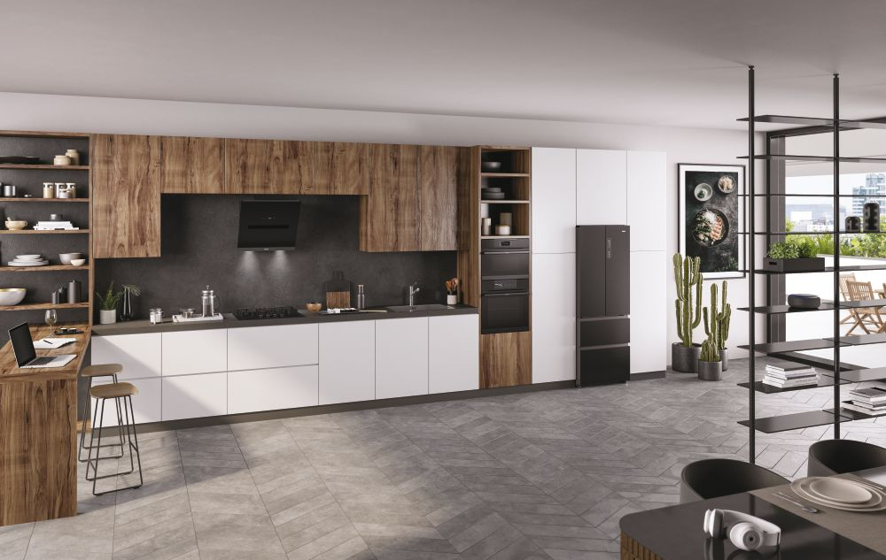 Una cocina moderna con gabinetes de madera y blancos, un refrigerador negro y una computadora portátil en el mostrador.
