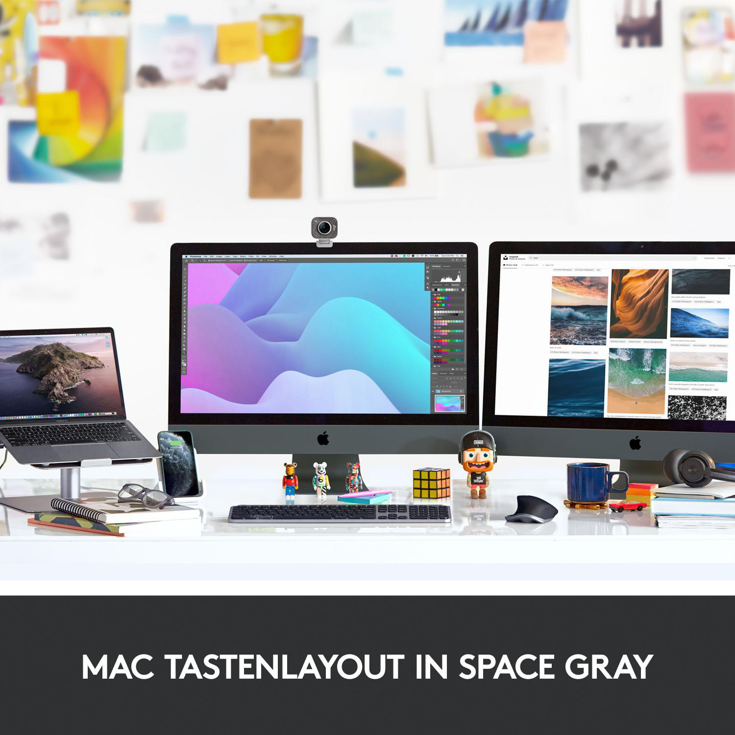 Arbeitsplatz mit zwei iMacs, MacBook auf Ständer, Telefon, Tastatur und Zubehör. Text: MAC TASTENLAYOUT IN SPACE GRAY.