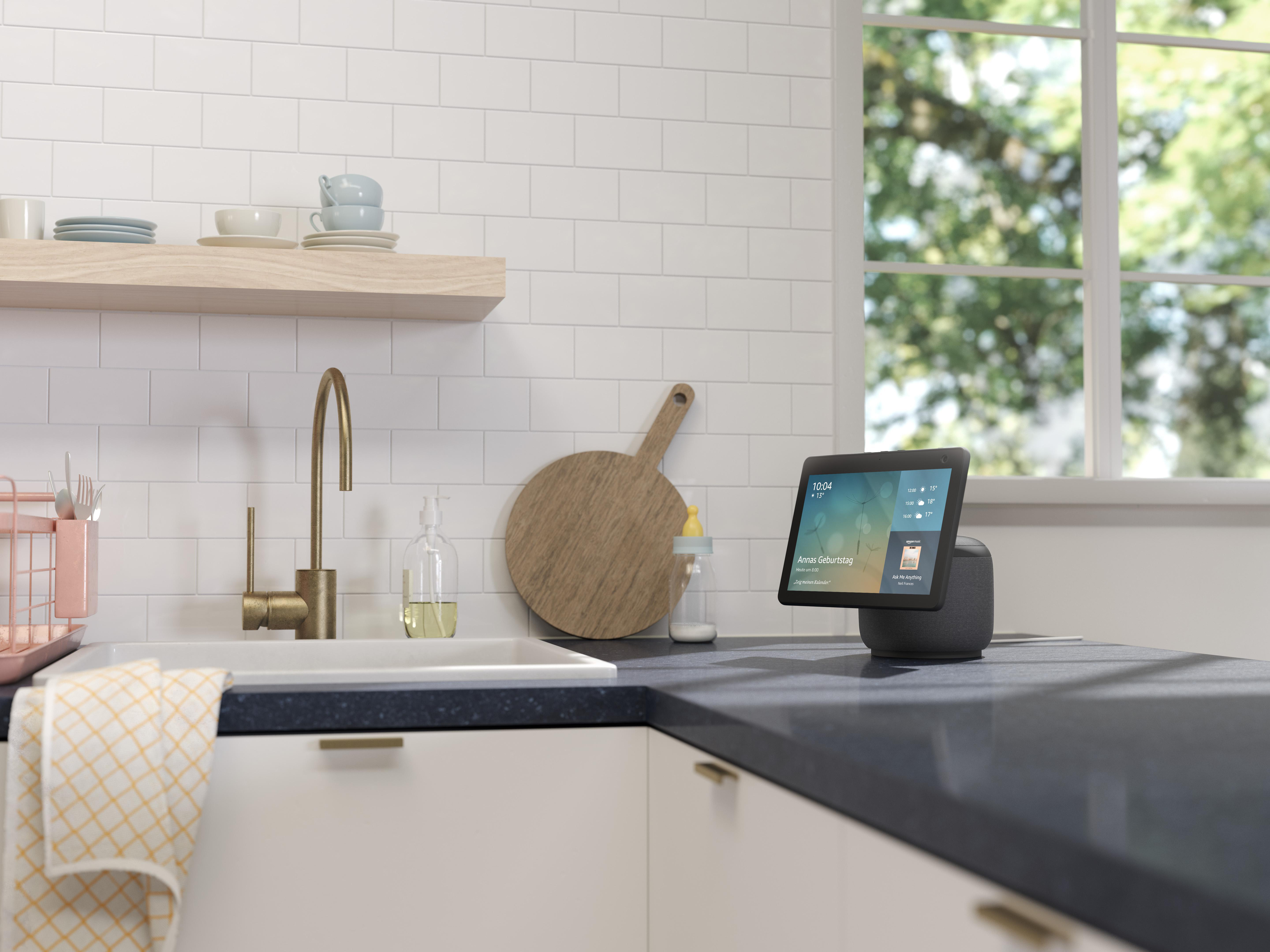 Küchentheke mit Smart-Display, Spüle, Holzschneidebrett und Fenster.