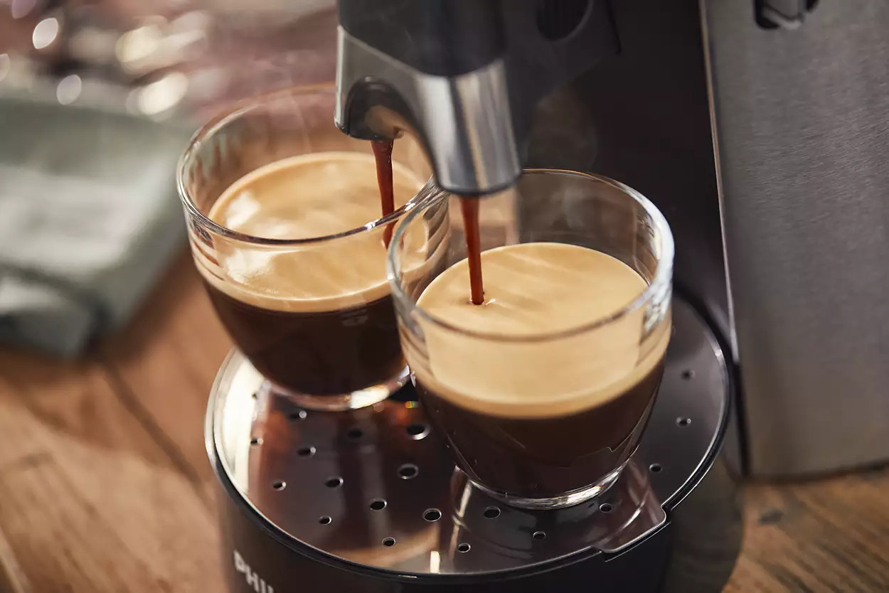 Deux verres remplis de café étant distribués par une machine à café.
