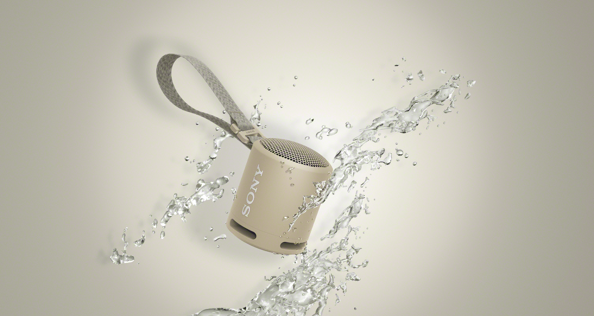 Petit haut-parleur beige avec logo Sony, éclaboussé d'eau sur fond clair.