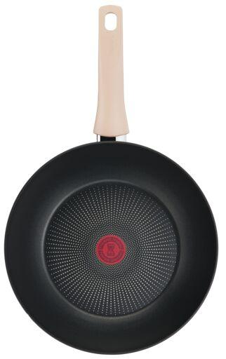 A black frying pan with a cream handle, red circle in the middle.
