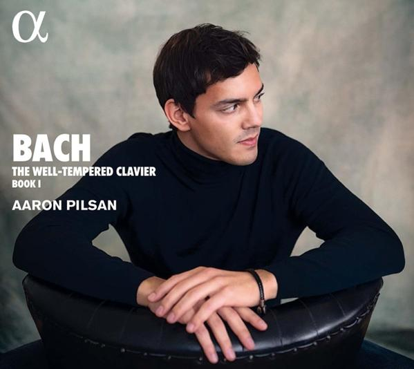 Un homme en col roulé regardant ailleurs. Le mot 'Bach' est écrit à gauche.