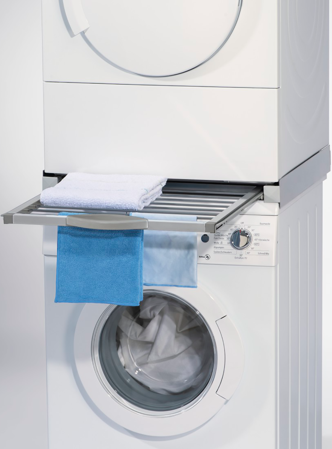 Een witte wasmachine en droger gestapeld, met een uittrekbaar droogrek.