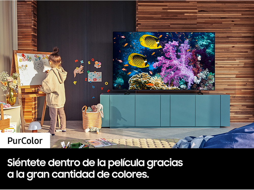 Un niño dibujando frente a un televisor que muestra peces de colores.