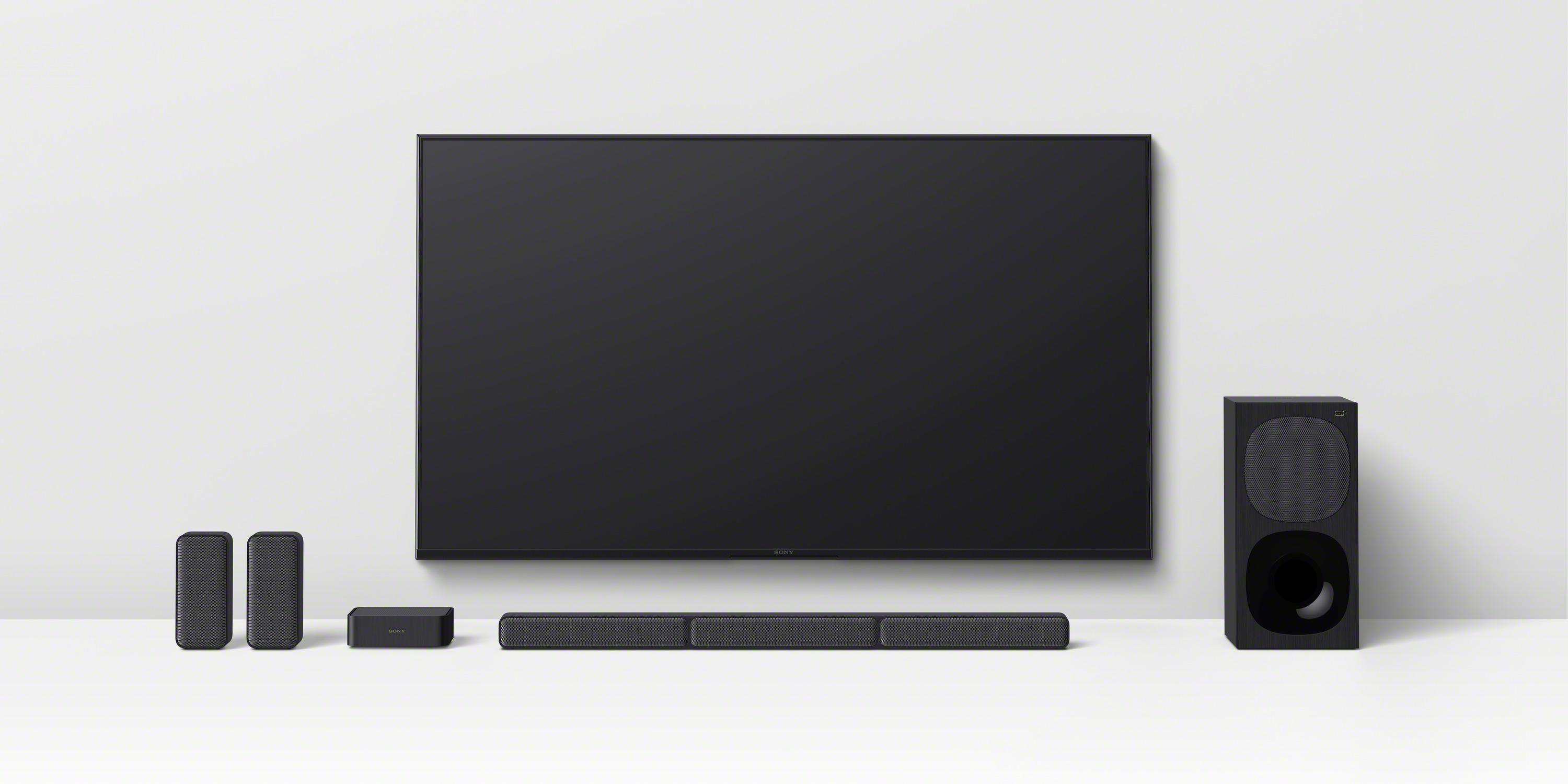 Ein Home-Entertainment-Setup mit großem Fernseher, Soundbar, Subwoofer und zwei kleinen Lautsprechern.