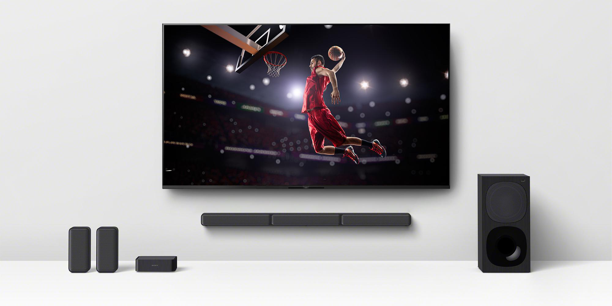 Wohnzimmereinrichtung mit Fernseher, Soundbar, Subwoofer und Lautsprechern.