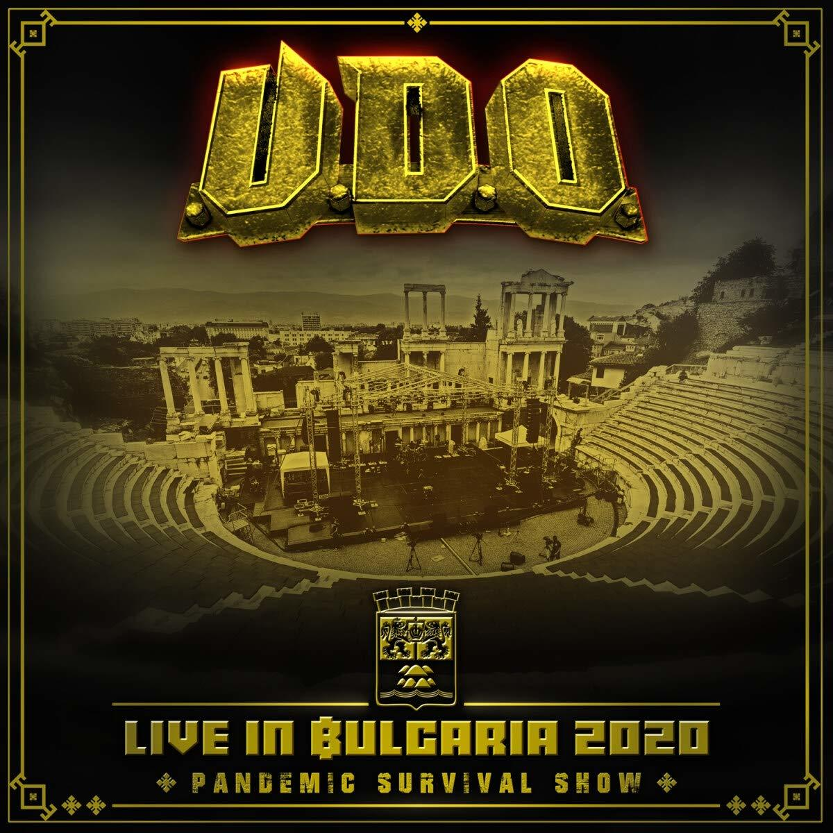 Albumcover mit goldenem Text 'U.D.O. Live in Bulgaria 2020'. Eine Bühne mit Publikum und ein historisches Gebäude.