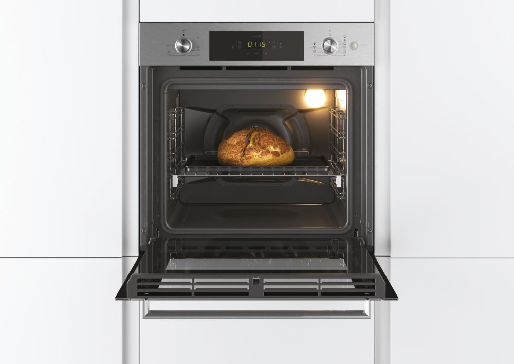 Horno con pan en una rejilla. Puerta abierta, luz encendida. Fondo de armarios blancos.