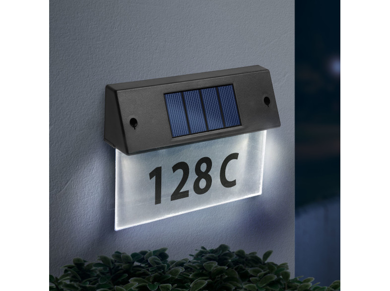 Egy világító, napenergiával működő címjelző, fekete kerettel, fehér, világító panellel, rajta '128 C'.