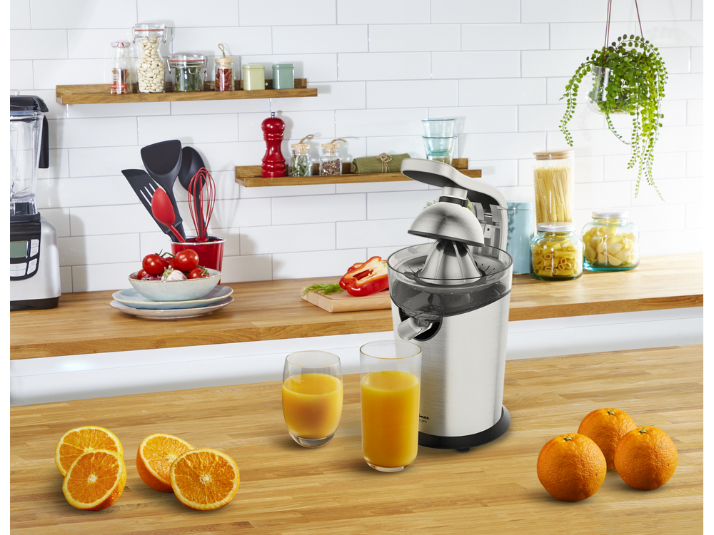 Una escena de cocina con una exprimidora, naranjas y dos vasos de zumo.