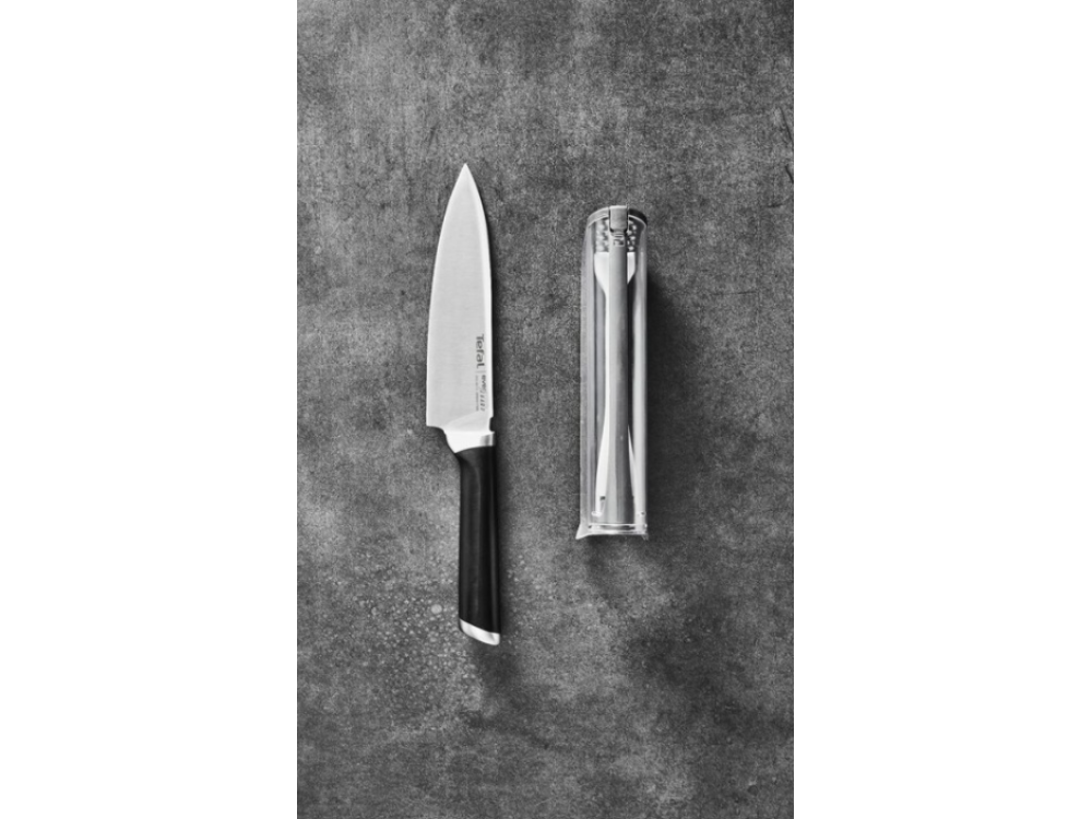 Cuchillo y cubiertos en un recipiente transparente sobre fondo gris.