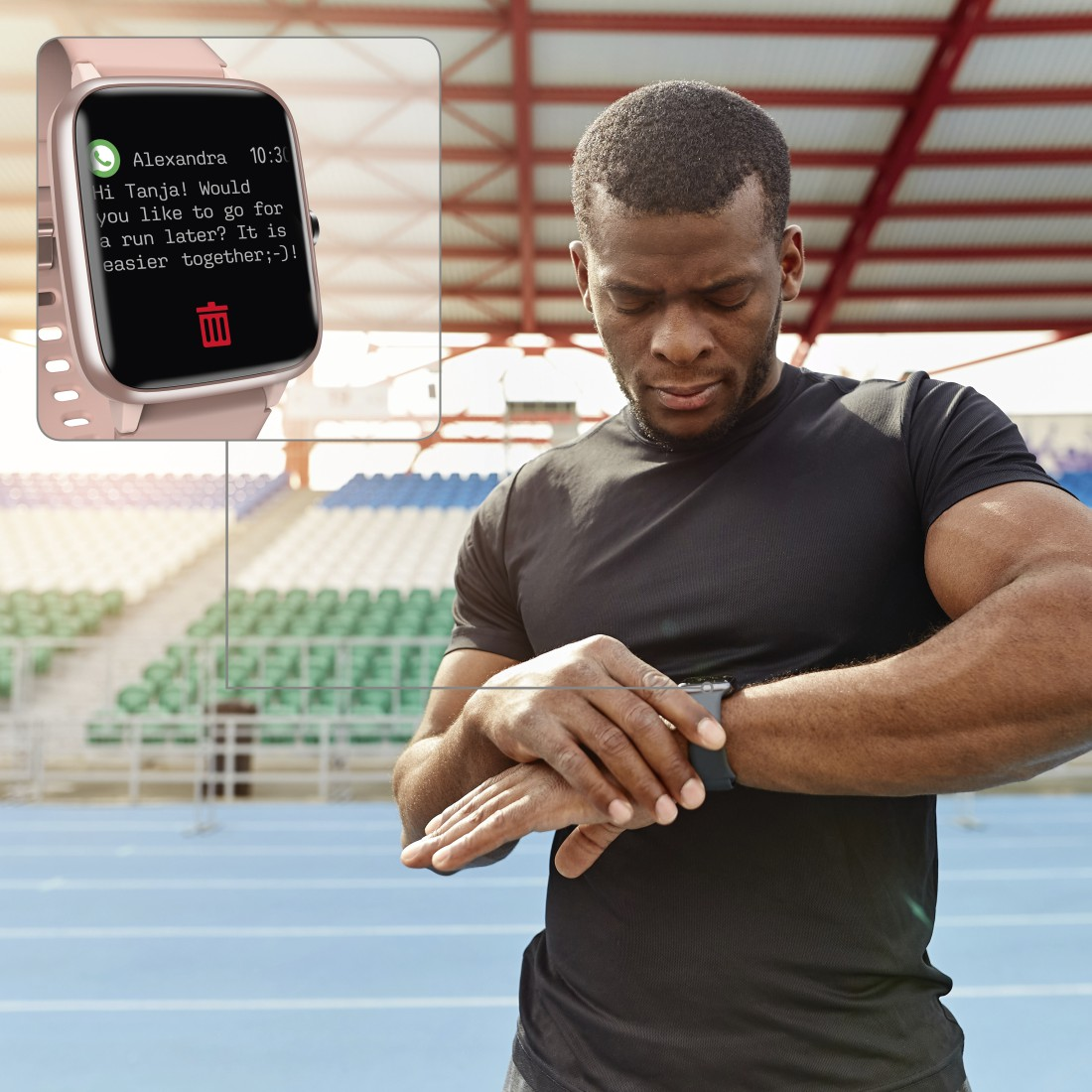 Ein Mann betrachtet eine Smartwatch mit einer Nachricht. Stadion im Hintergrund.