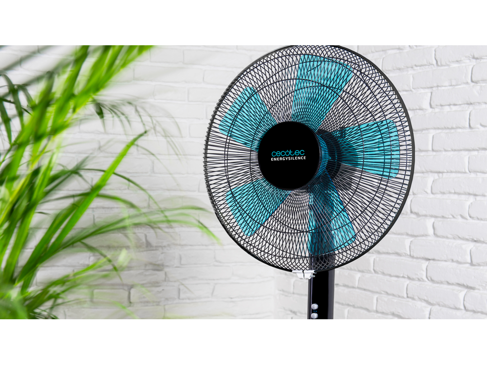 Ventilador negro y turquesa sobre soporte. Pared de ladrillos blancos al fondo.