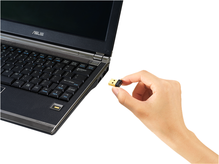 Egy kéz, amely egy kis USB vezeték nélküli adaptert tart egy laptop billentyűzete mellett. Az adapter fekete és arany.