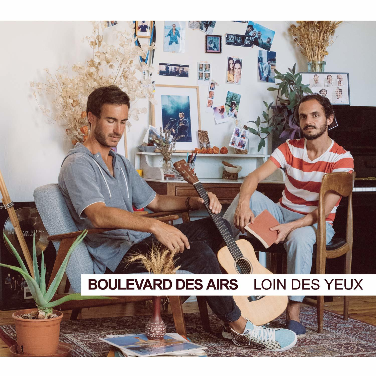 Deux hommes assis dans une pièce avec une guitare et un livre. Texte: 'Boulevard des Airs' et 'Loin des yeux'.