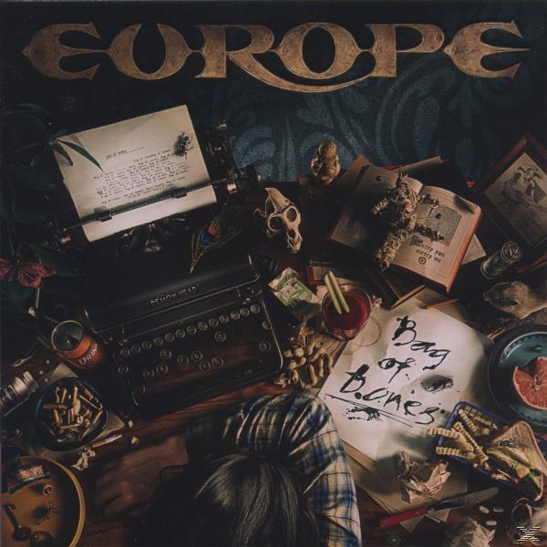Album borító egy asztalról, tárgyakkal, írógéppel, koponyával, egy pohár folyadékkal és egyéb tárgyakkal.