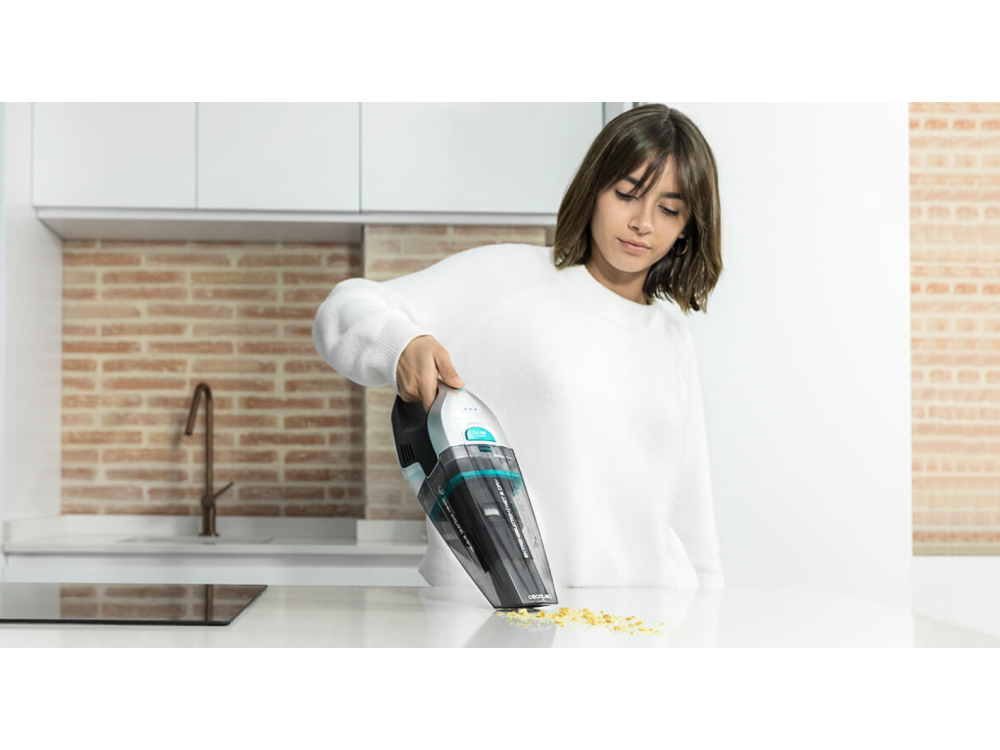 Una mujer aspirando una encimera blanca en una cocina moderna.