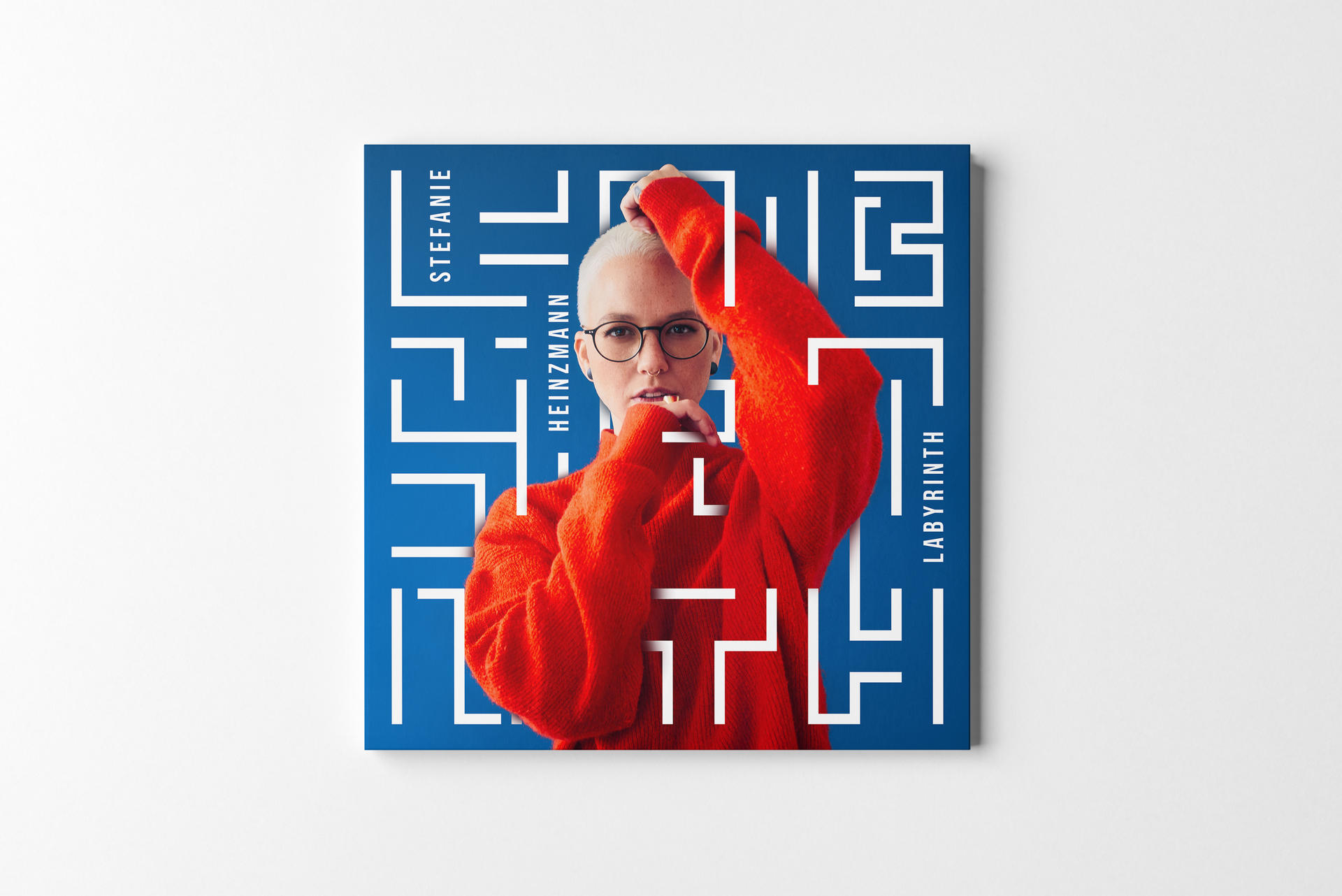 Ein quadratisches Albumcover mit einer Frau und einem Labyrinth-Design auf blauem Hintergrund.