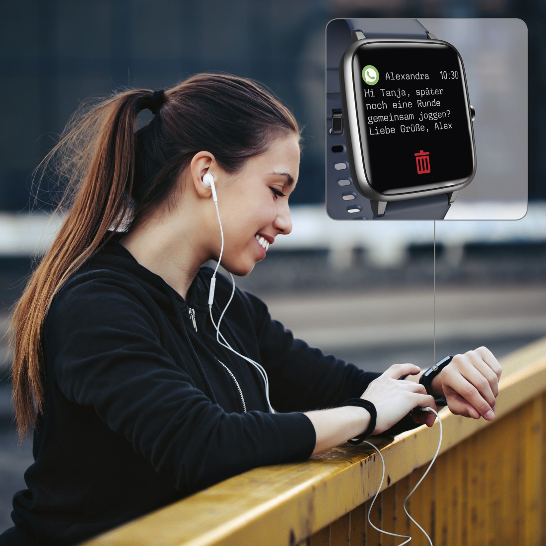 Eine Frau, die auf eine Smartwatch mit einer Textnachricht schaut, lächelt, mit Kopfhörern.