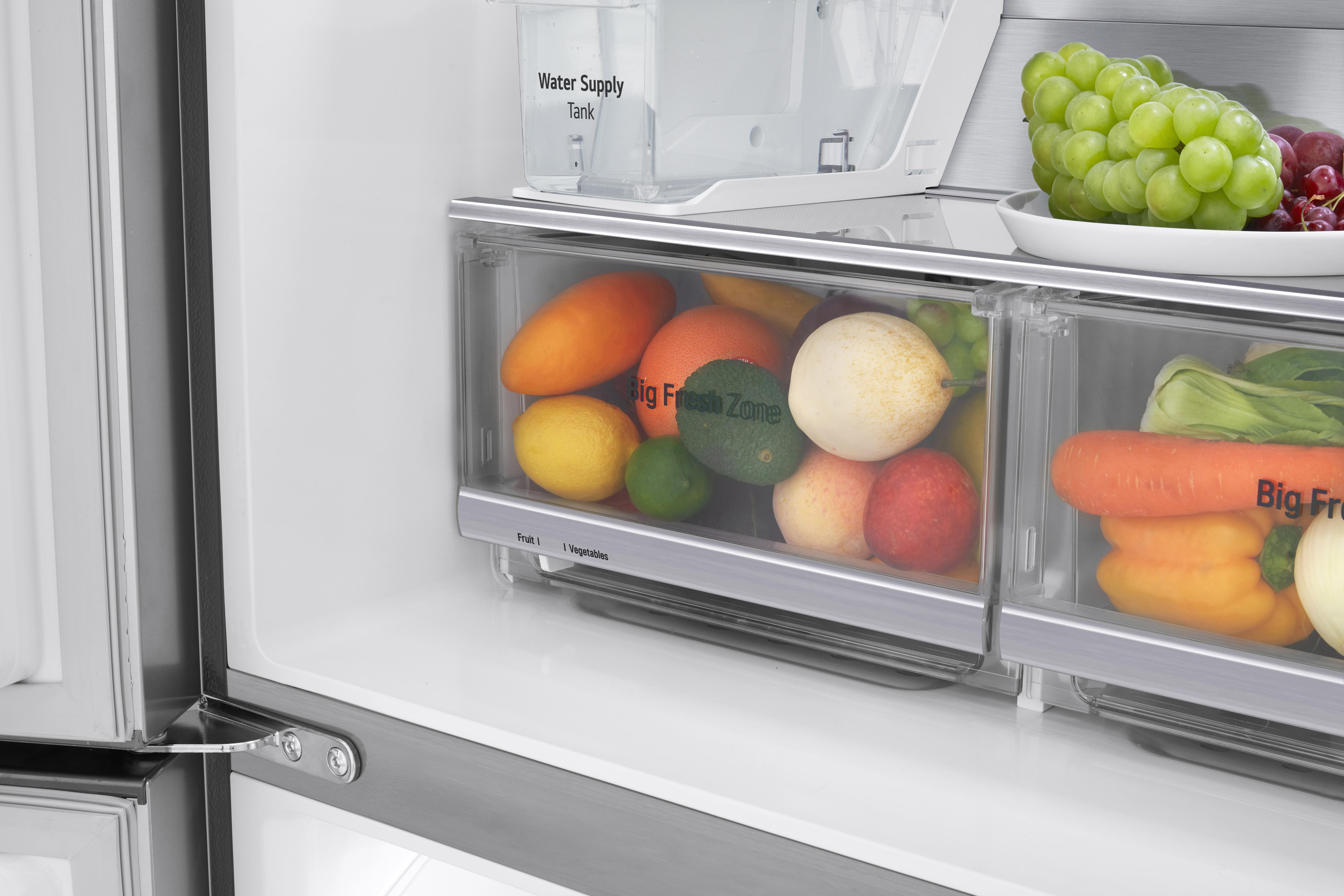 Kühlschrankinnenraum mit Obst und Gemüse in transparenten Schubladen und einem Wassertank.