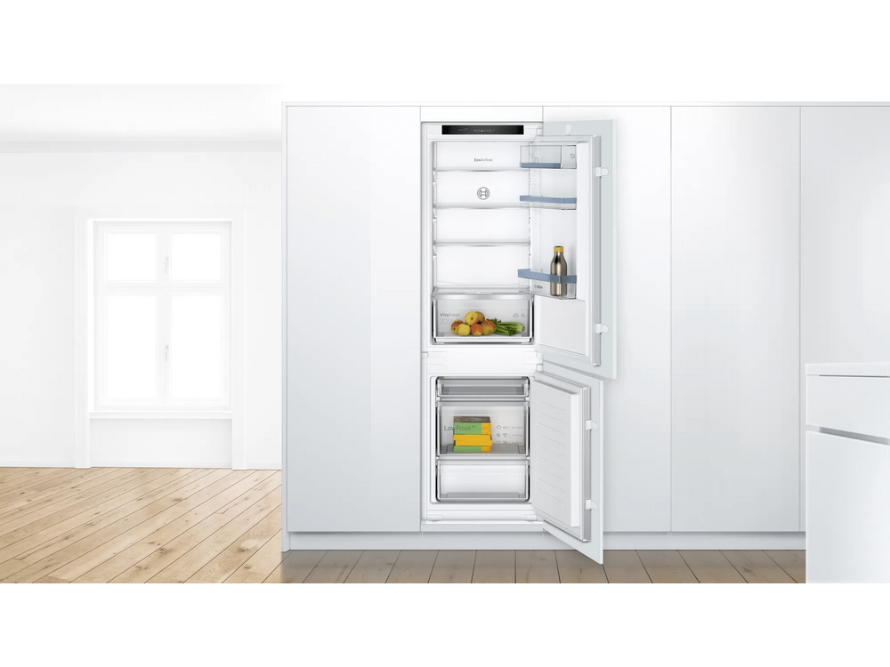 Un refrigerador empotrado con puertas abiertas, mostrando estantes, cajones y alimentos.