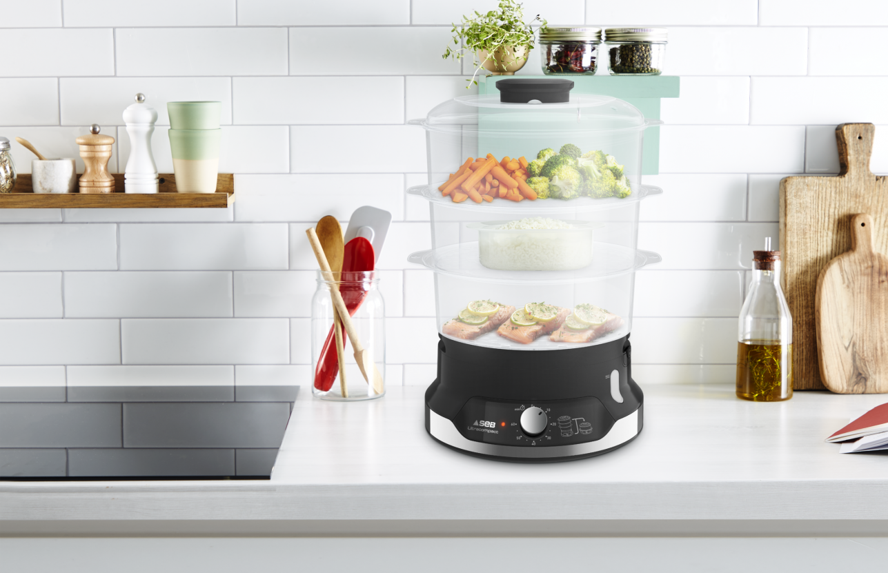 A multi-tier food steamer on a white countertop. It is full of food and ready to cook.