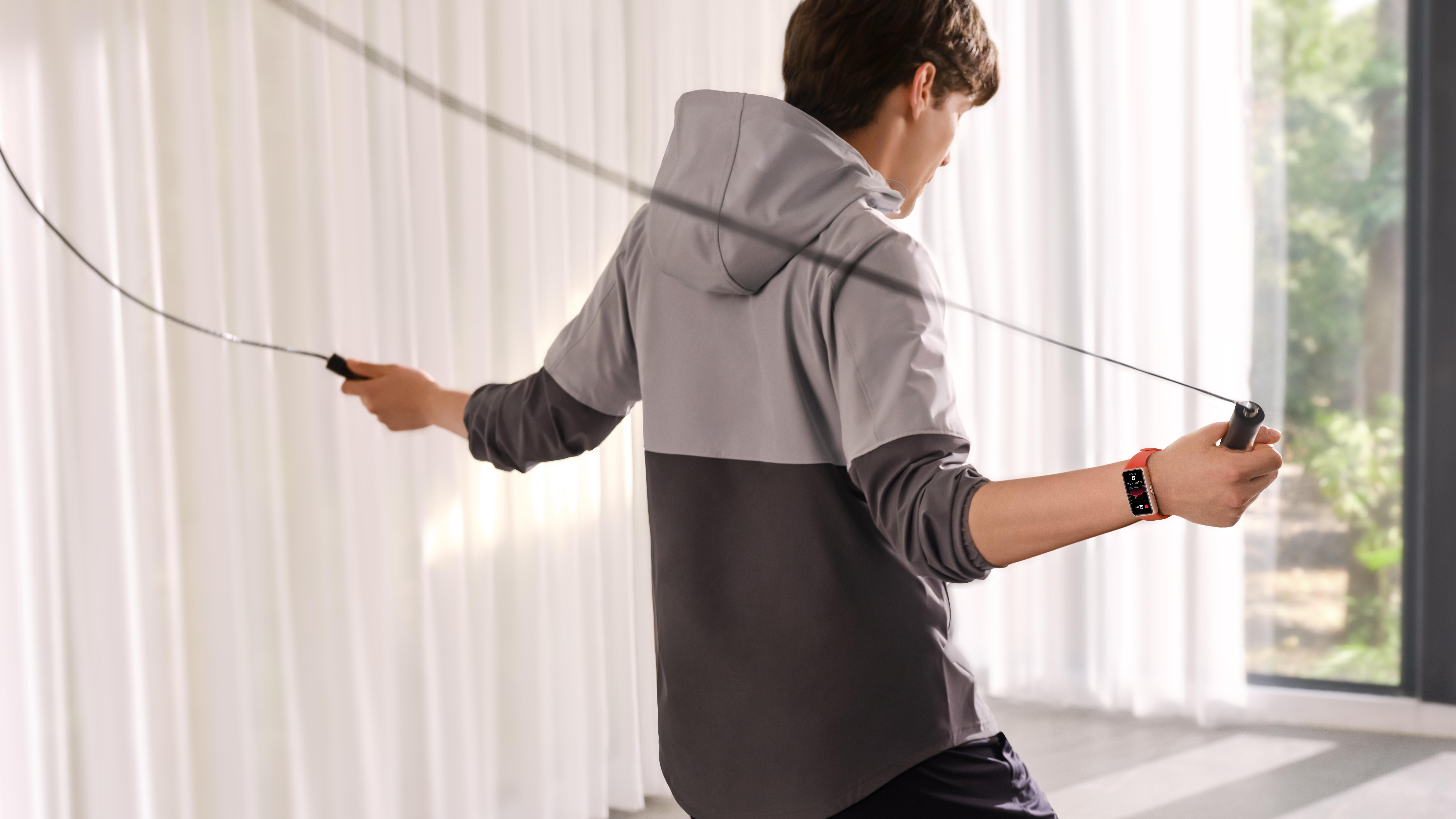 Person springt Seil, trägt Fitness-Tracker am Handgelenk. Innenaufnahme mit natürlichem Licht.