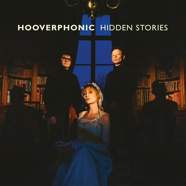 Pochette d'album avec trois personnes dans une bibliothèque, avec le titre 'Hidden Stories'.