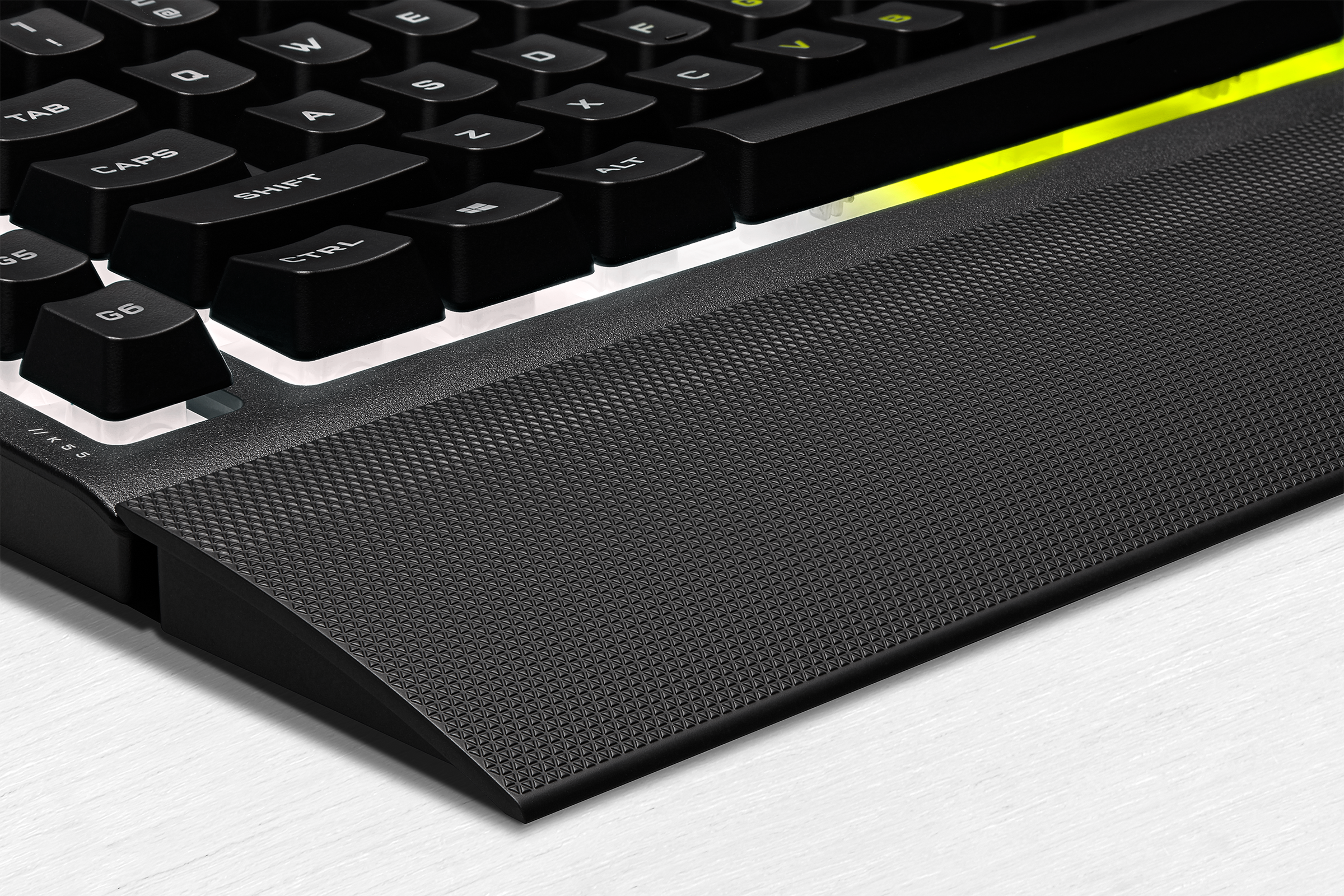 Gros plan sur un clavier avec repose-poignet, texture noire et touches illuminées.