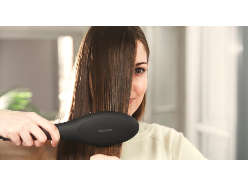 Mujer usando un cepillo alisador negro. Su cabello es largo, castaño y liso.