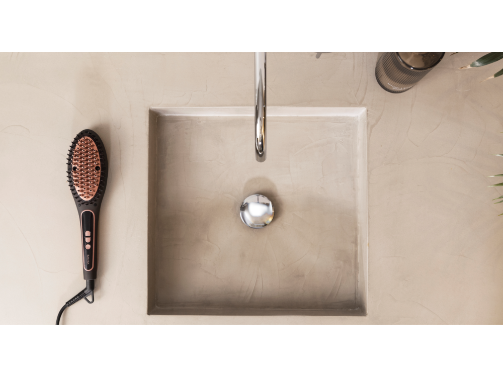 Escena de baño: un lavabo con grifo y un cepillo alisador de pelo al lado.
