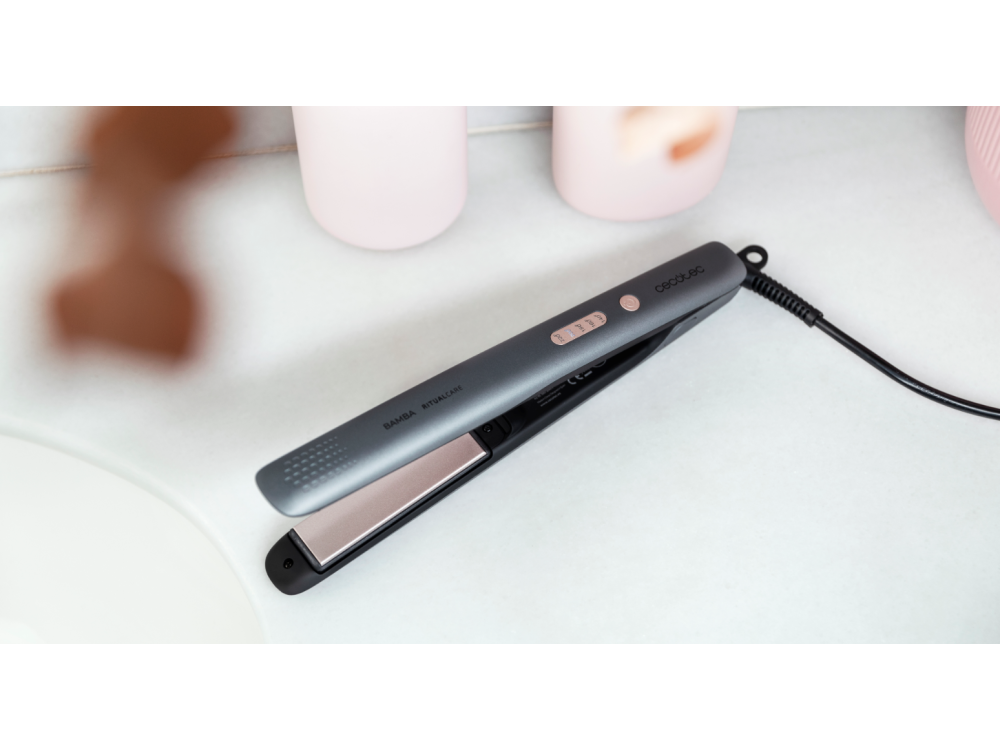 Plancha de pelo gris sobre superficie blanca, cable de alimentación negro, visible la marca.