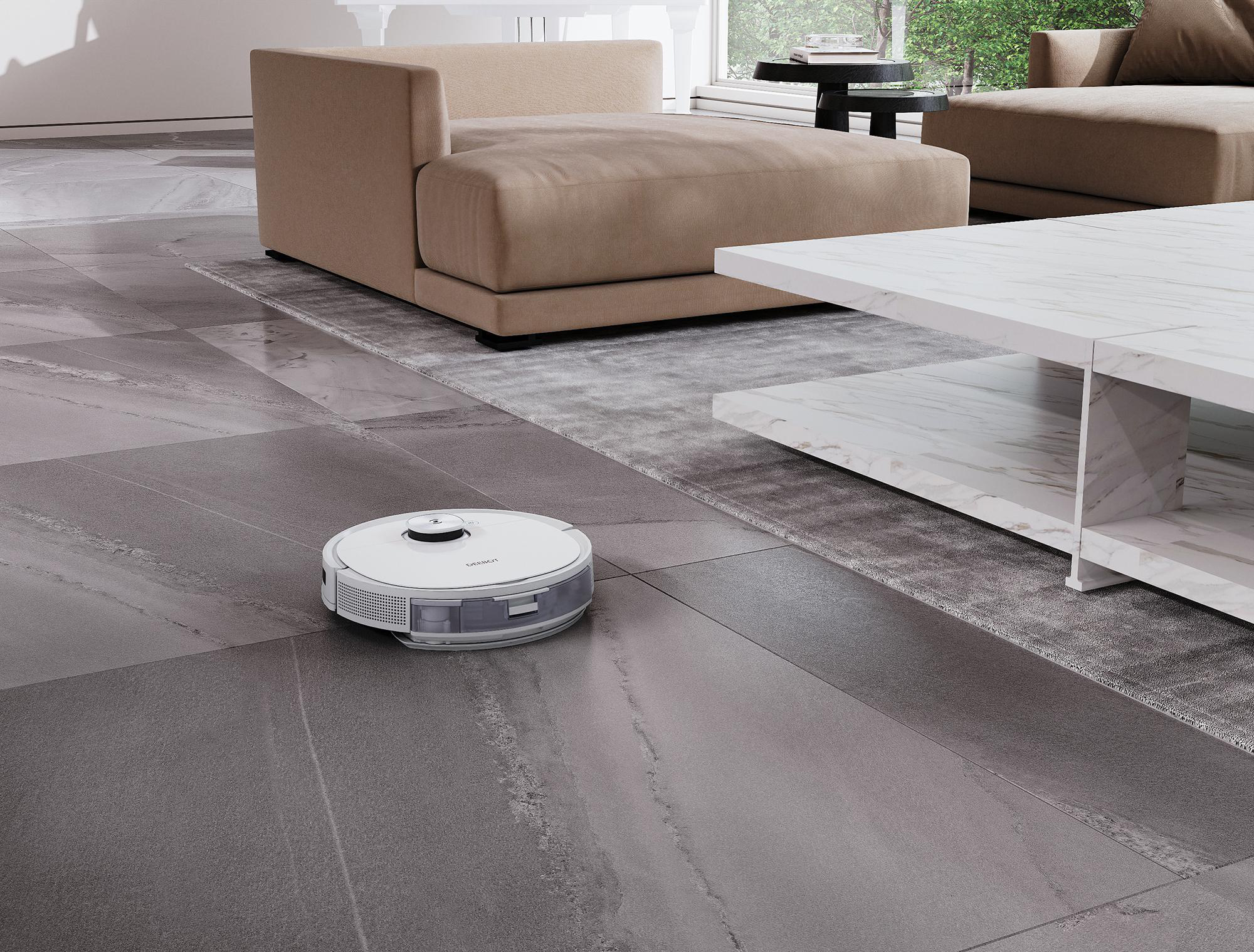 Roboter-Staubsauger auf grauem Fliesenboden, in einem modernen Wohnzimmer.