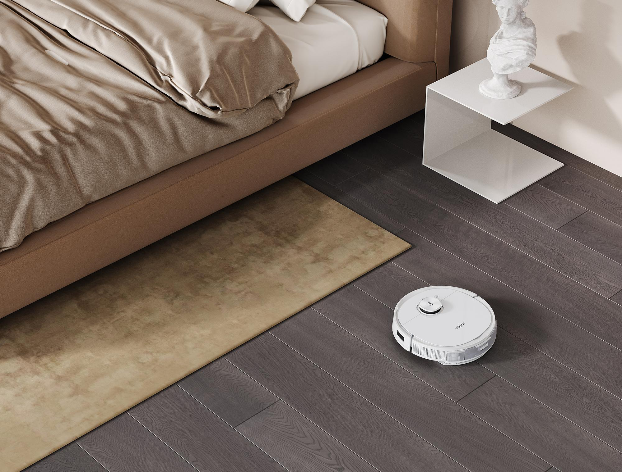 Ein weißer Roboter-Staubsauger auf einem dunklen Holzboden neben einem beigen Teppich und einem Bett. Eine weiße Skulptur.