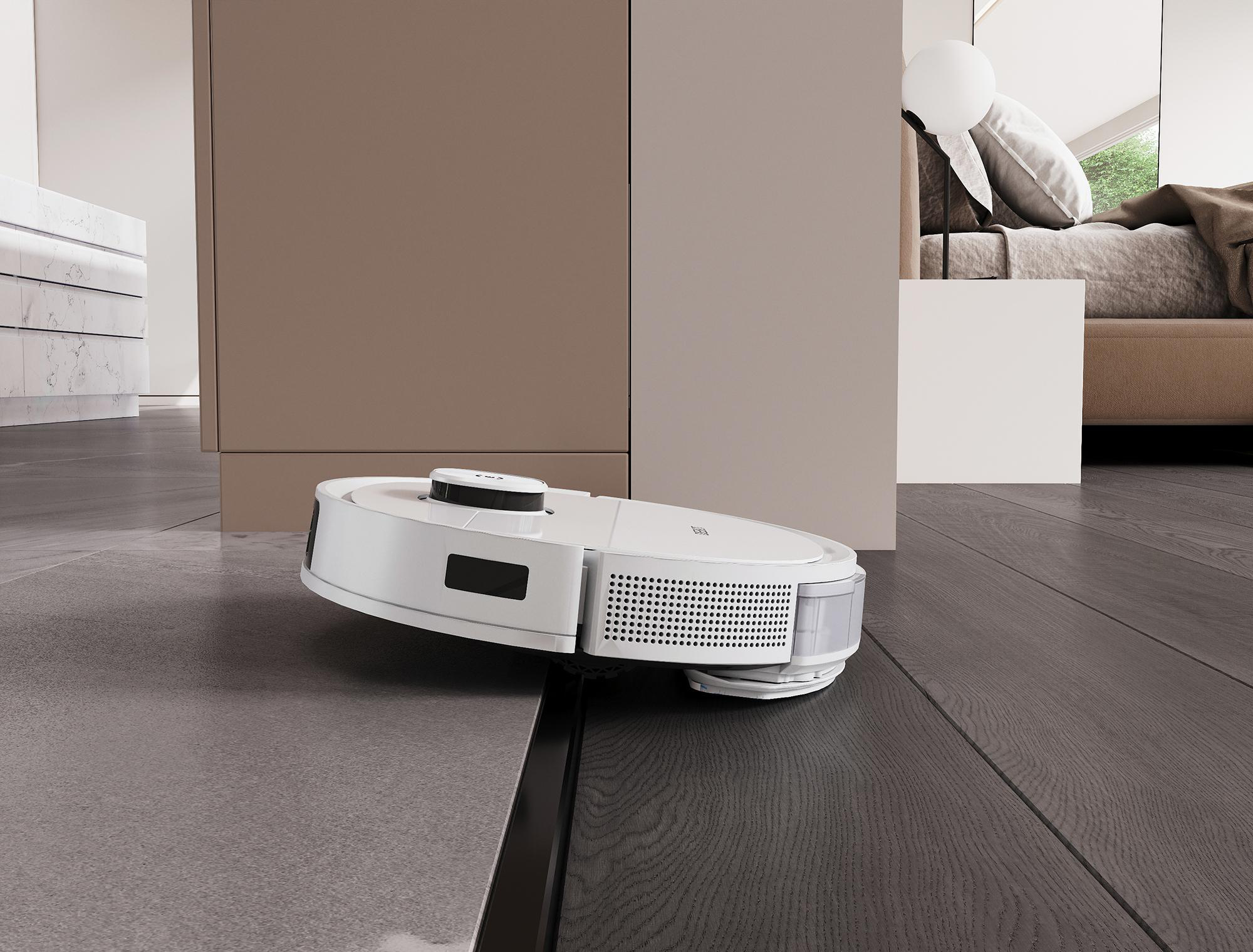 Ein weißer Roboter-Staubsauger auf einem grauen Boden. Ein Schlafzimmer und andere Möbel sind im Hintergrund.