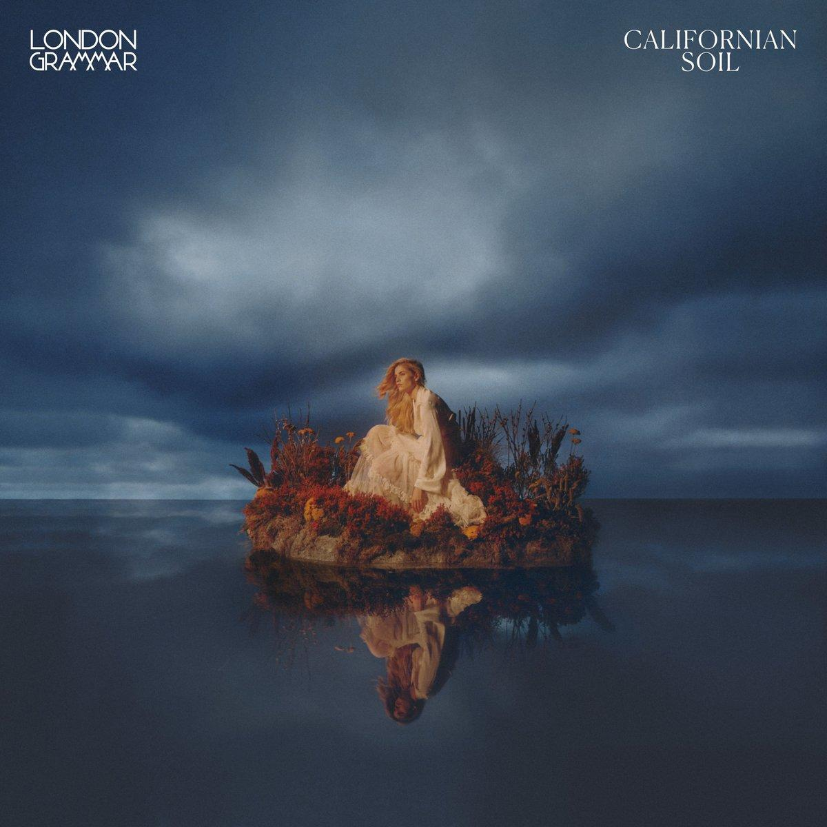 Pochette d'album avec une femme assise sur une petite île dans l'eau sous un ciel dramatique.