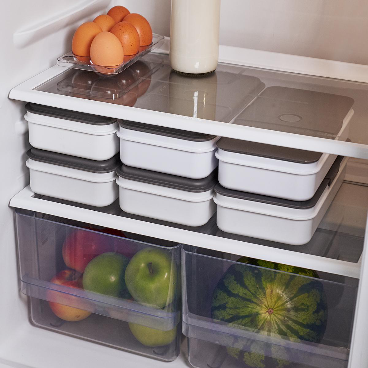 Offener Kühlschrank mit Lebensmitteln. Eier, Äpfel und Behälter mit Lebensmitteln sind sichtbar.