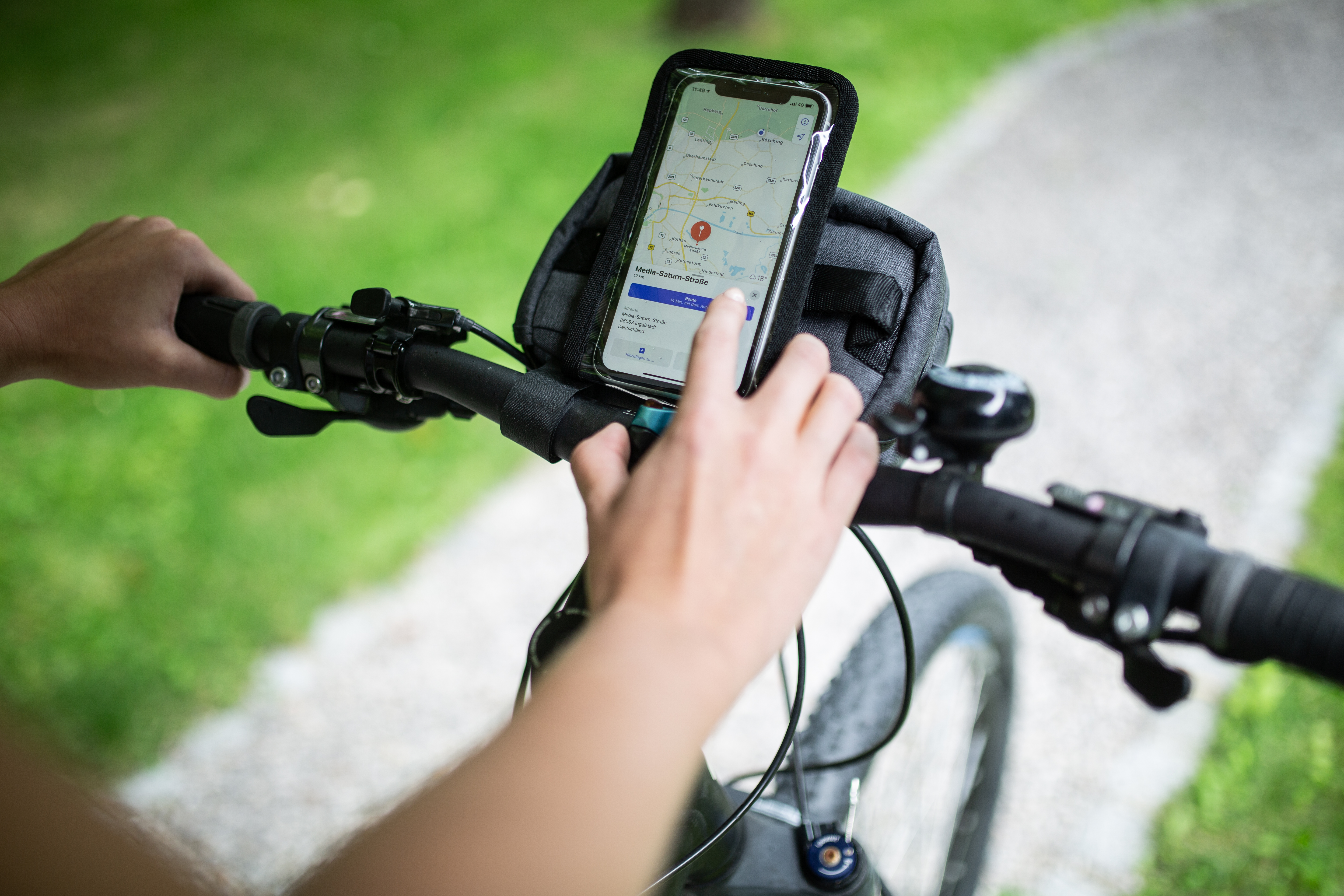 Hände halten Fahrradlenker, Telefon in Halterung montiert.
