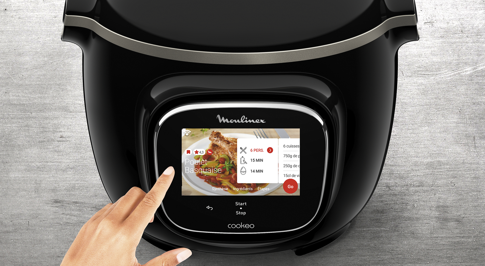 A black Moulinex Cookeo. A hand is touching the screen showing a recipe for Poulet Basque.