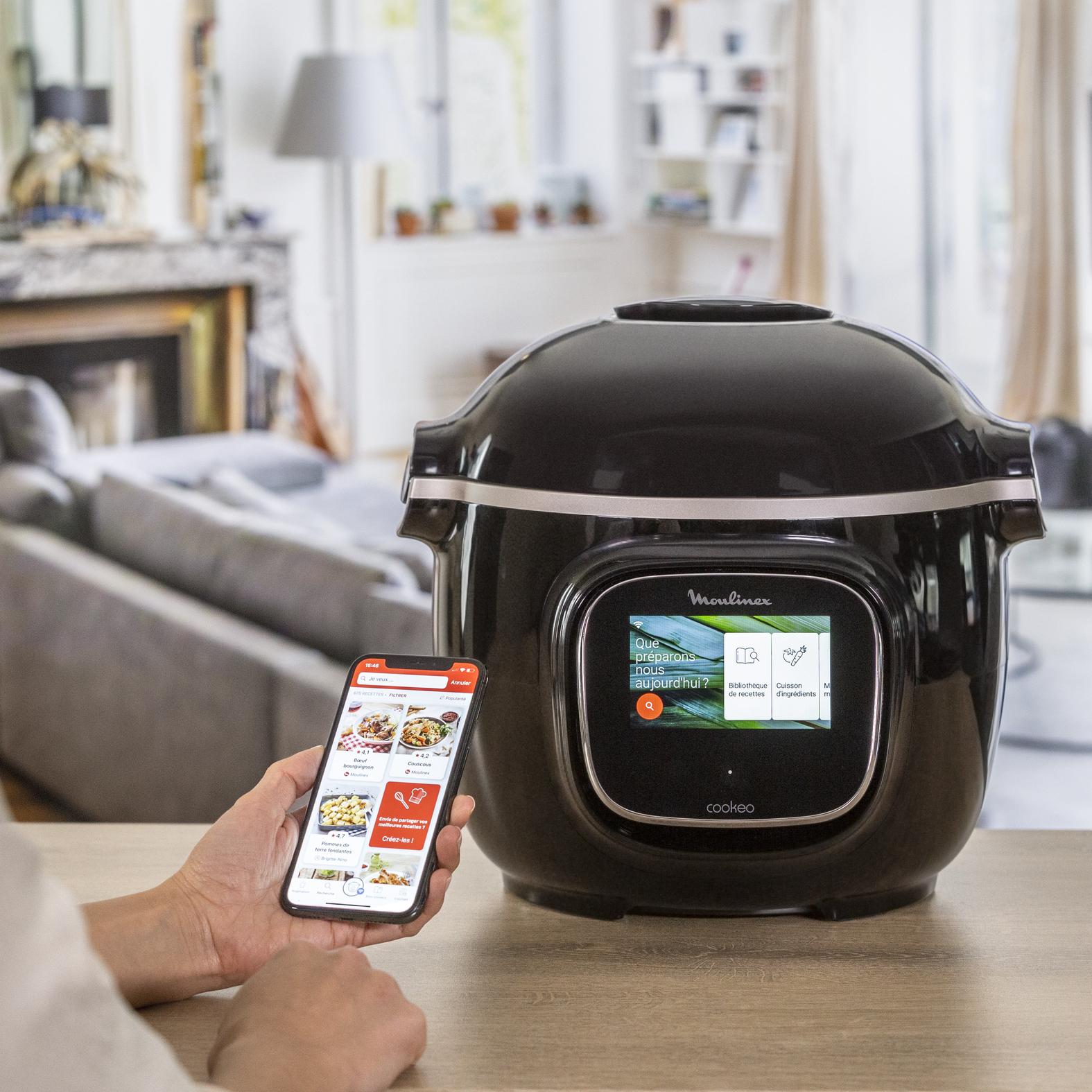 A black Moulinex appliance with a smartphone displaying a recipe application.