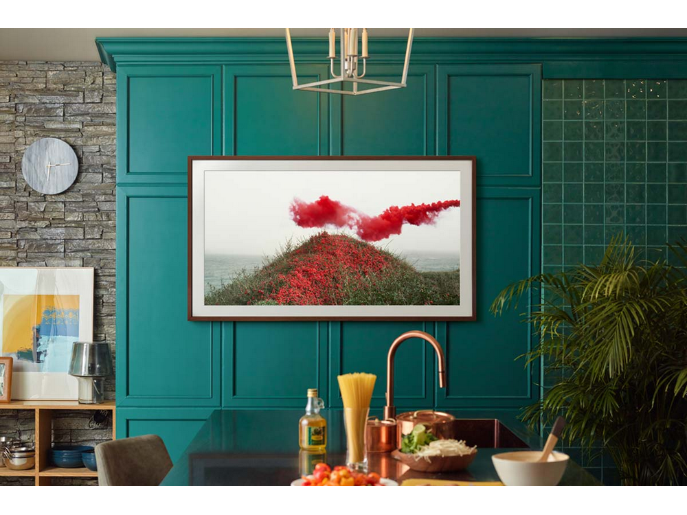 Cocina con TV mostrando paisaje con humo rojo. Gabinetes verde oscuro.