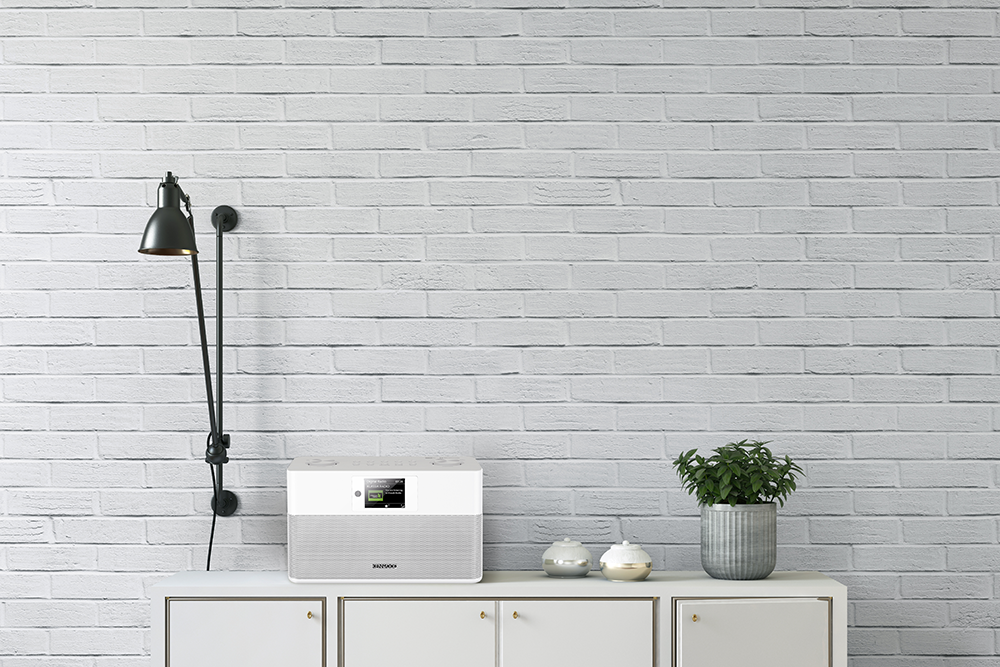 Witte bakstenen muur met een witte kast en een lamp. Radio en plant in pot op de kast.