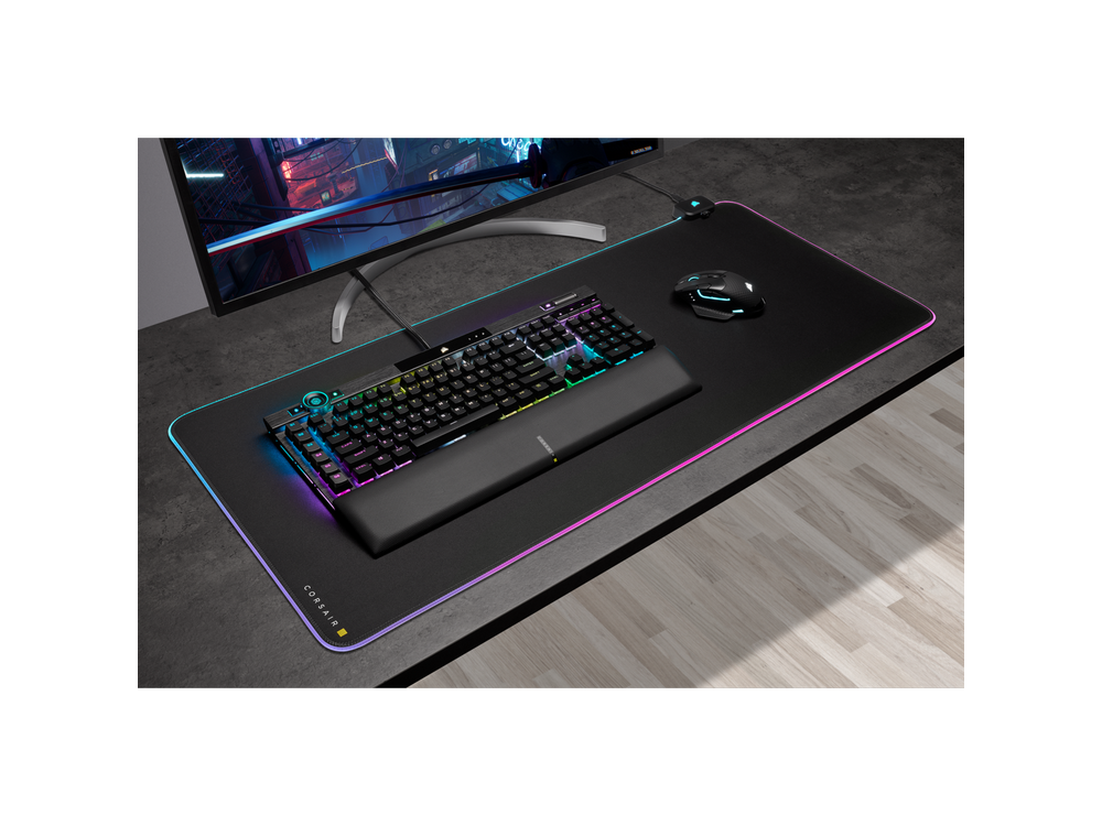 Configuración de juego con teclado negro, ratón y una alfombrilla de ratón grande con iluminación RGB.