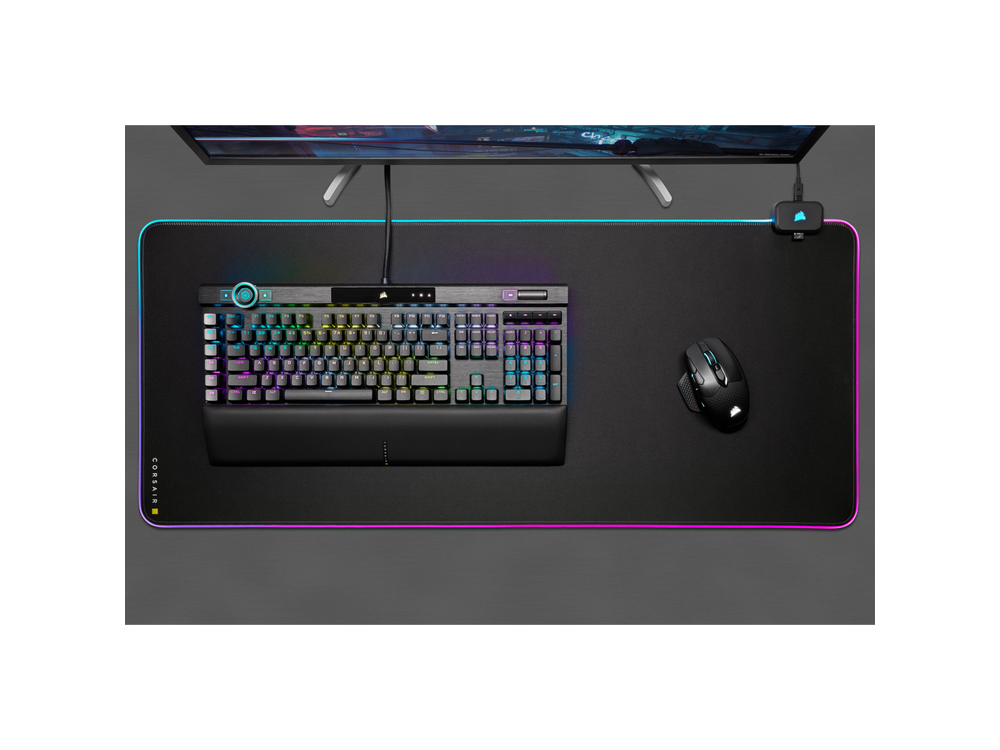Vista cenital de una configuración de juego, incluyendo teclado, ratón, alfombrilla y monitor Corsair.