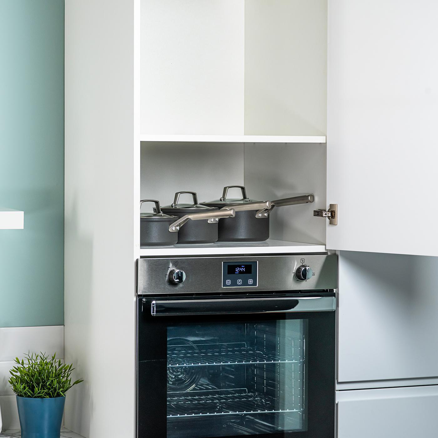 Küchenschränke und Backofen. Pfannen sind im Schrank über dem Ofen gelagert.