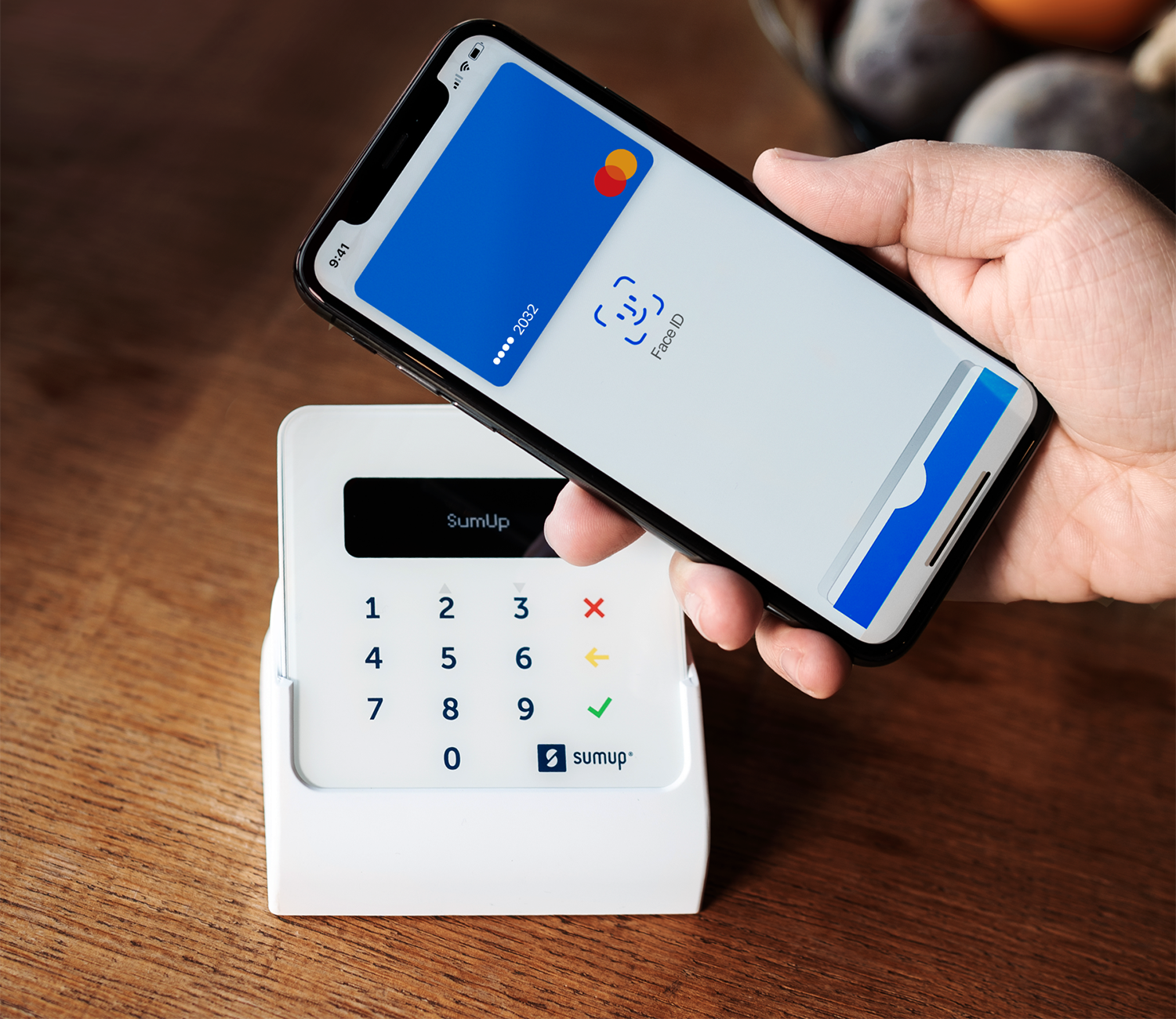 Telefoon boven een SumUp betaalterminal met creditcard op het scherm.