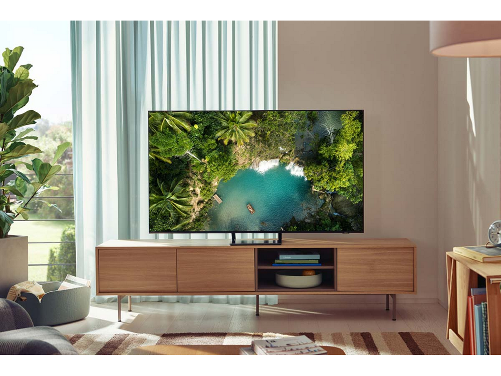 Una sala de estar moderna con un televisor que muestra una vista panorámica, encima de un mueble de madera.