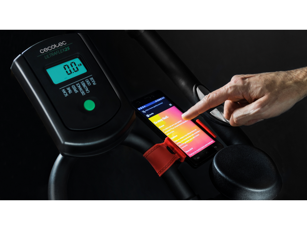 Una mano toca un teléfono inteligente en una bicicleta estática. La pantalla es colorida.