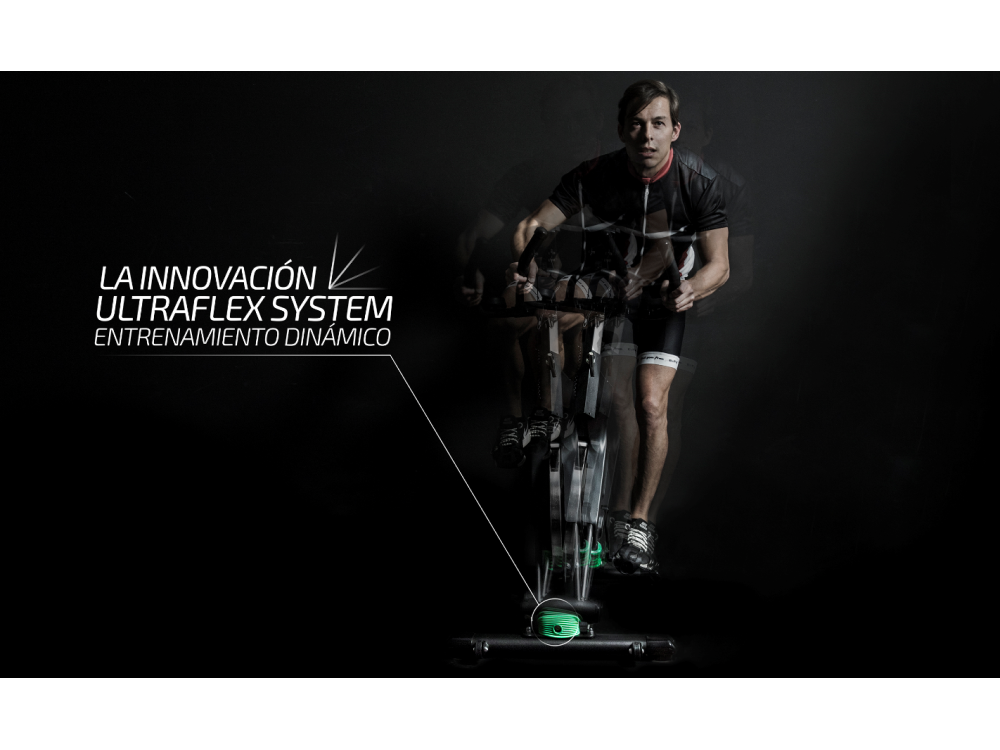 Hombre en bicicleta estática. Texto: LA INNOVACIÓN ULTRAFLEX SYSTEM, ENTRENAMIENTO DINÁMICO. Fondo negro.